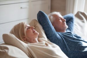 Calm mature couple relaxing on sofa having daytime nap together